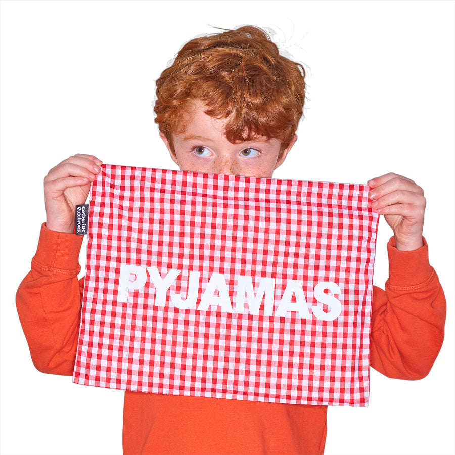 Catherine Colebrook red gingham pyjama case with bold white ‘pyjamas' text on the front being held by young boy