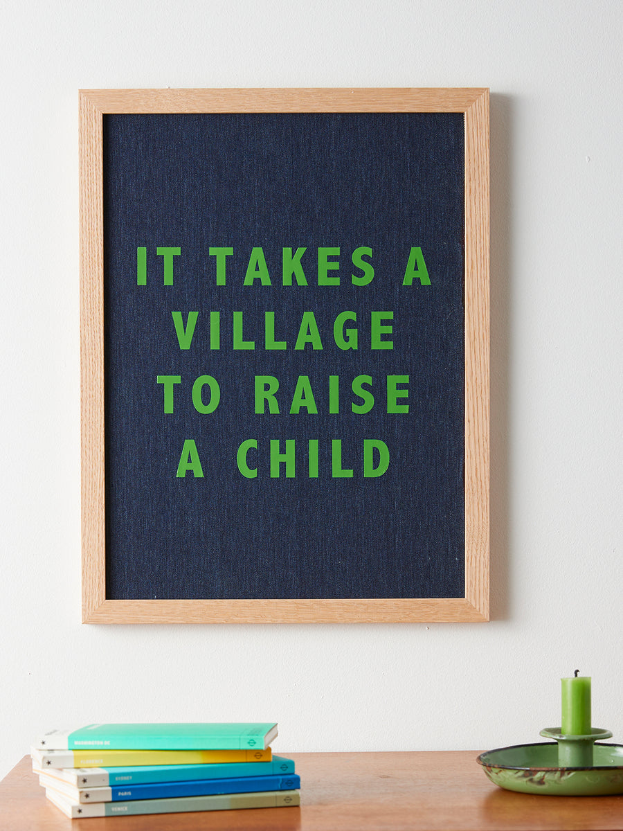 Catherine Colebrook framed denim quote picture, ‘It Takes a Village to Raise a Child' in denim with green text, in an oak frame