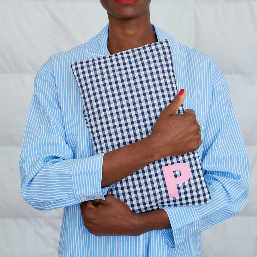 smiling woman hugging navy gingham hot water bottle, personalised with pink P