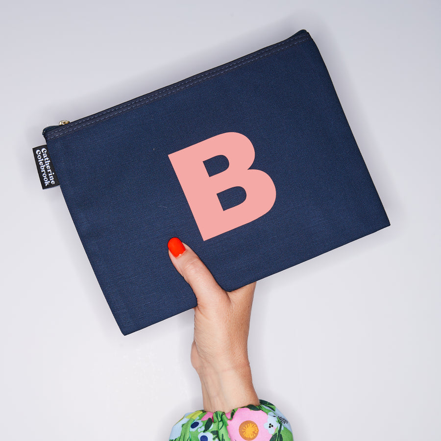 HAND HOLDING LARGE COTTON NAVY PURSE WITH AN SALMON PINK LETTER B ON IT