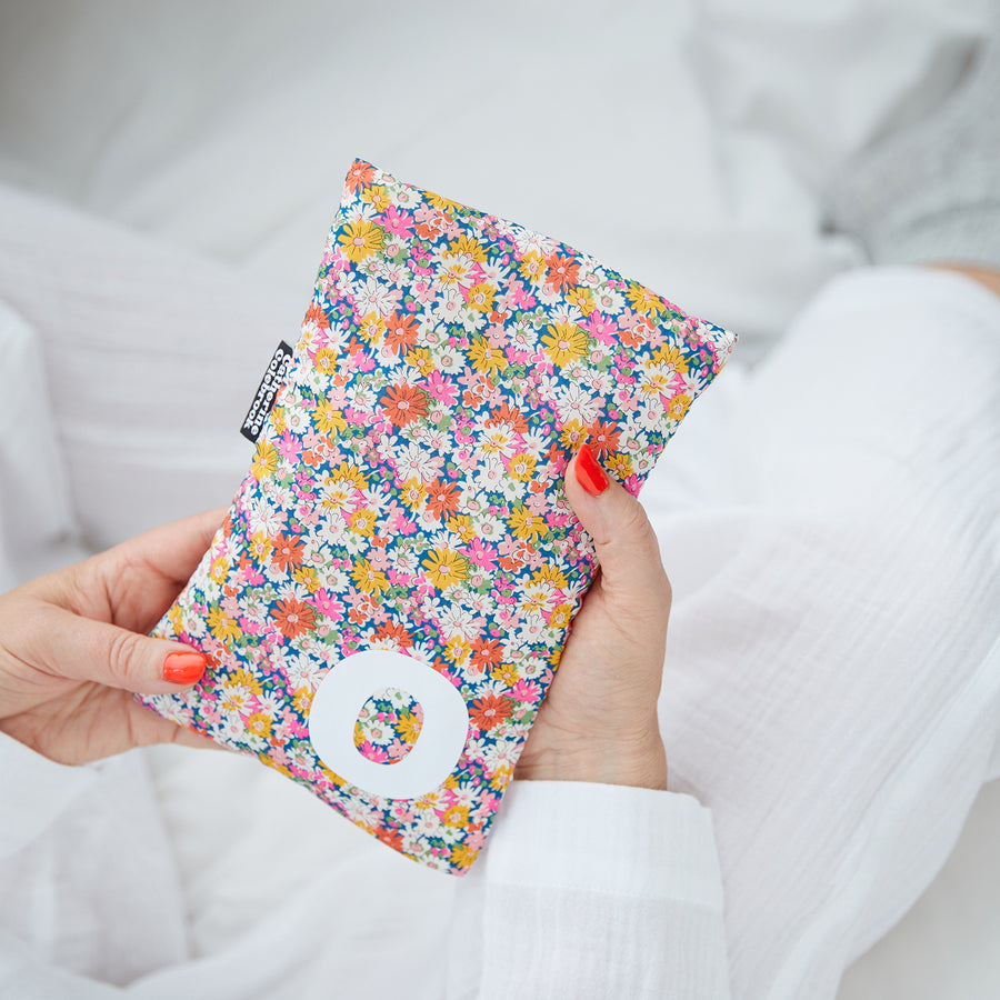 Hand holding cute hot water bottle in Pink Yellow Liberty print, personalised with a white letter O.