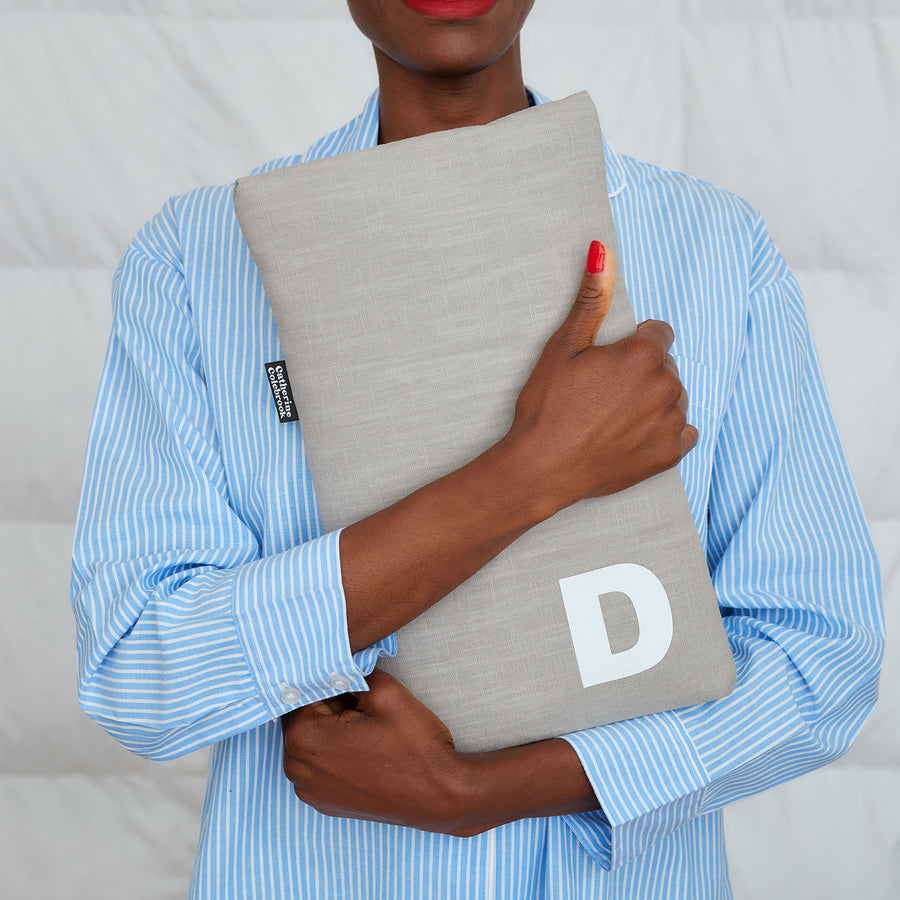 smiling woman hugging grey linen hot water bottle, personalised with white D