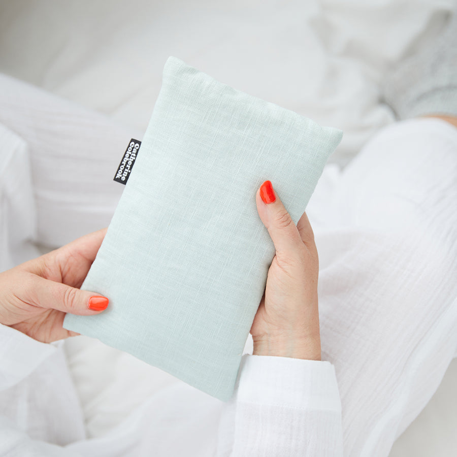 Hand holding cute hot water bottle in Mint Linen.