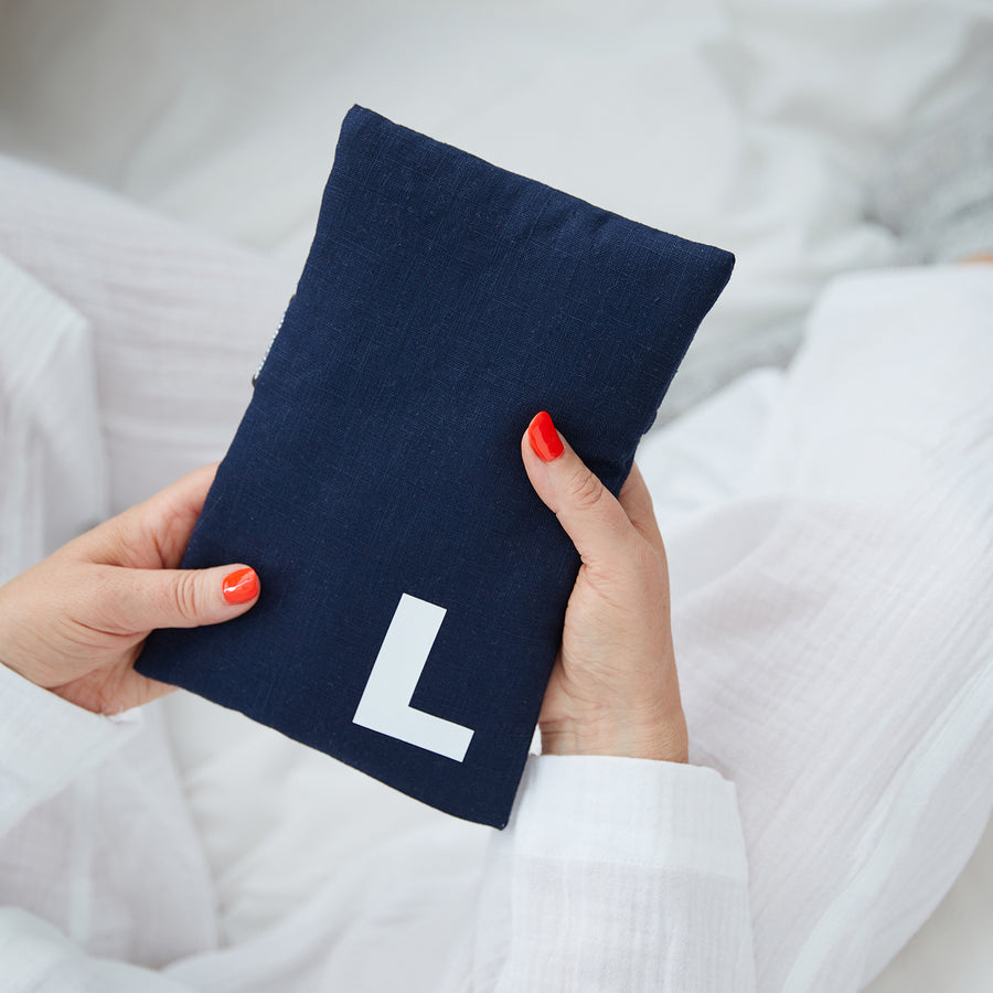 Hand holding cute hot water bottle in Navy Linen, personalised with a white letter L.
