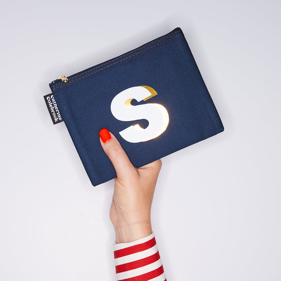 HAND HOLDING MEDIUM COTTON NAVY PURSE WITH A WHITE LETTER S ON IT