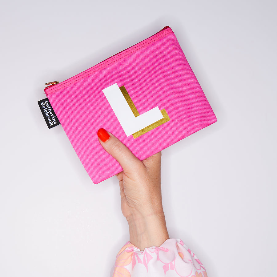 HAND HOLDING MEDIUM COTTON PINK PURSE WITH A WHITE LETTER L ON IT