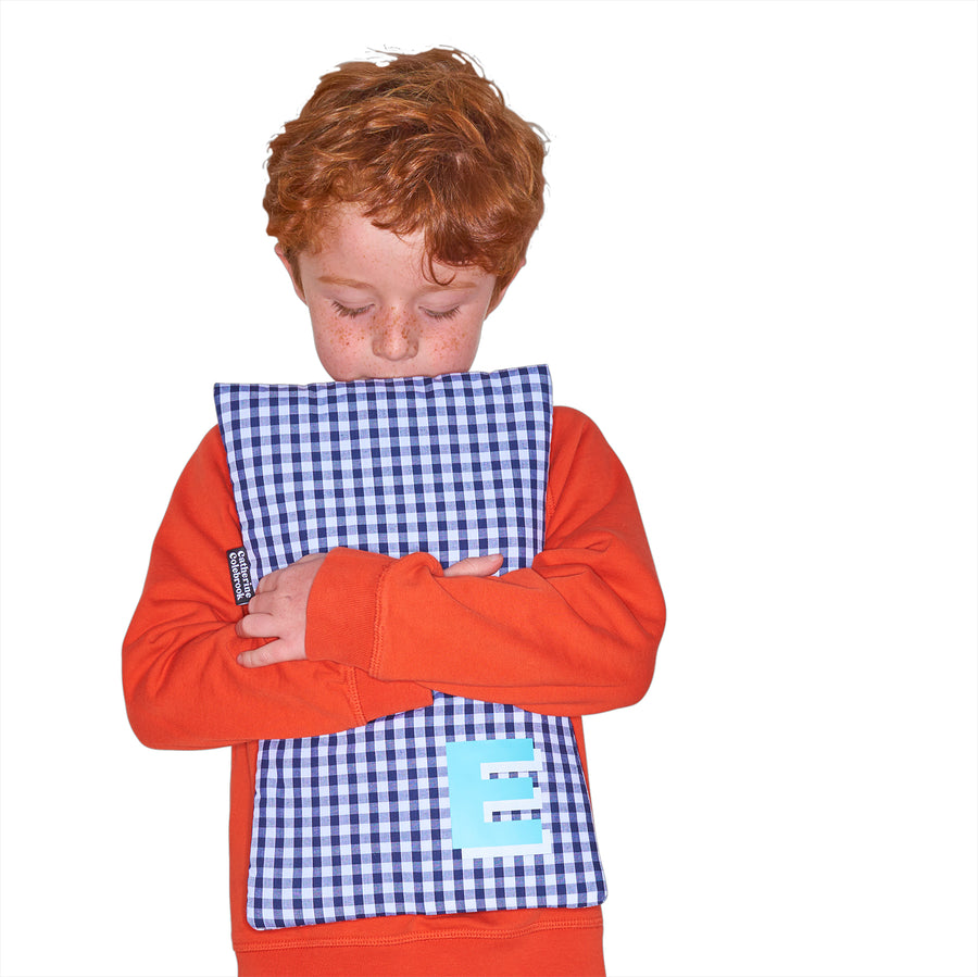 Catherine Colebrook navy gingham hot water bottle with ‘3D’ style initial in bottom right corner in turquoise with white highlights being held by young boy