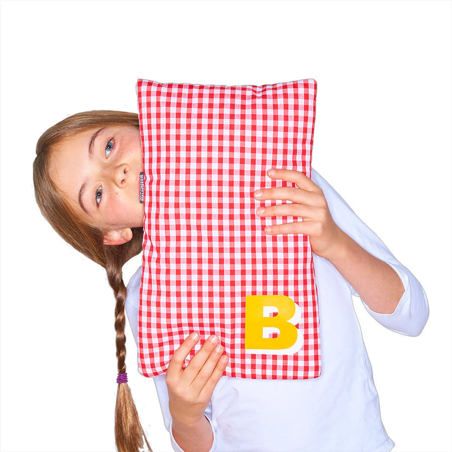 Catherine Colebrook red gingham hot water bottle with ‘3D’ style initial in bottom right corner in yellow with white highlights being held by young girl