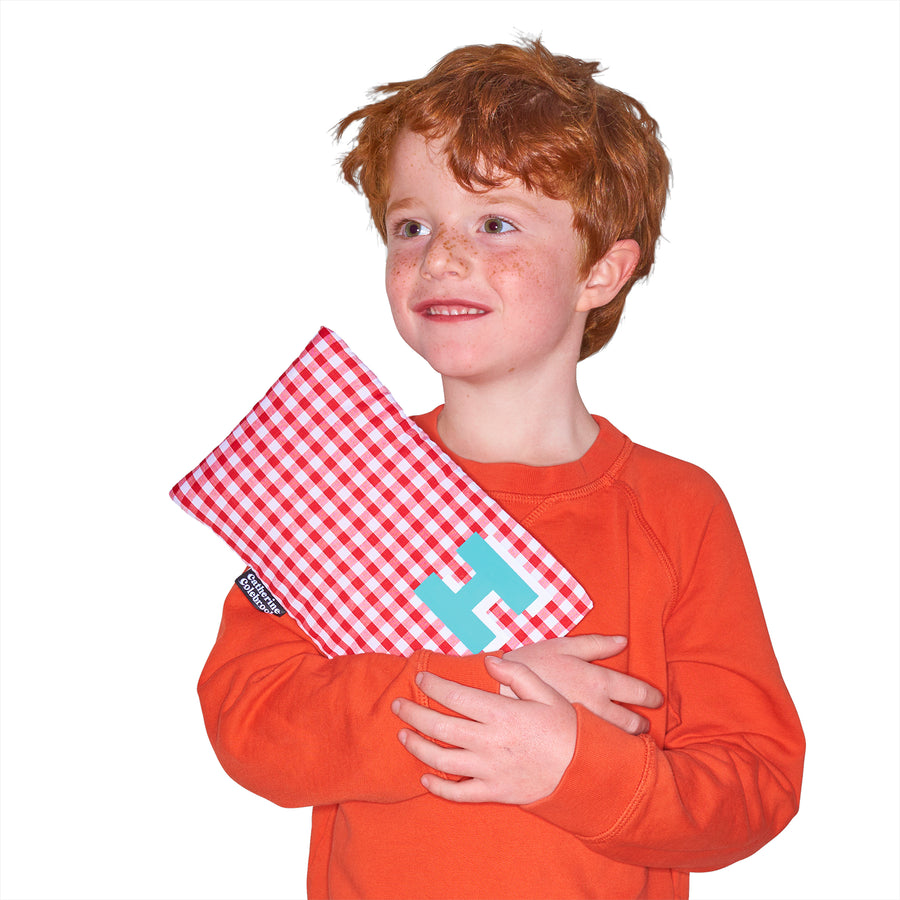 Catherine Colebrook cute red gingham hot water bottle with ‘3D’ style initial in bottom right corner in turquoise with white highlights being held by young boy